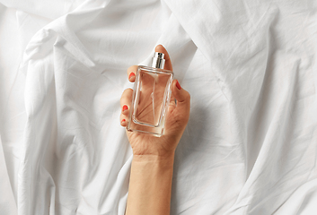 Image showing female hand with bottle of perfume on white sheet