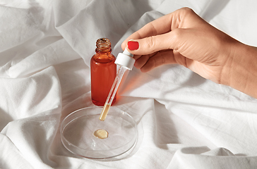 Image showing female hand with dropper applying serum to glass