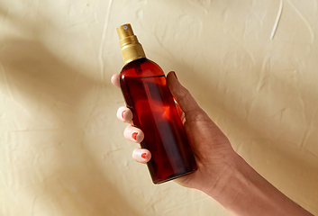 Image showing close up of hand with bottle of sunscreen oil