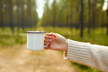 Image showing hand of woman with white tea mug in forest