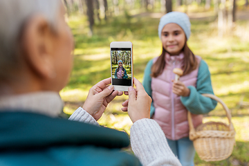 Image showing grandma photographing granddaughter with mushrooms