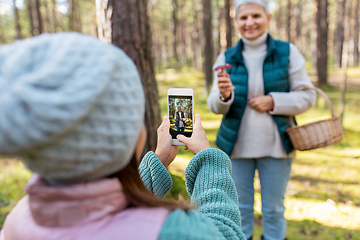 Image showing granddaughter photographing grandma with mushrooms