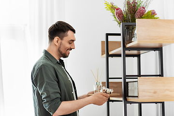 Image showing man placing aroma reed diffuser to shelf home