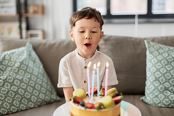 Image showing happy little boy blowing candles on birthday cake