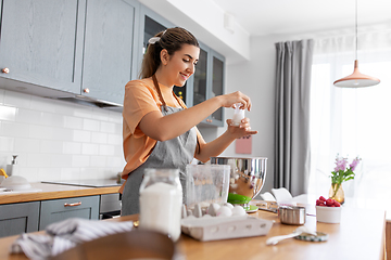 Image showing happy young woman cooking food on kitchen at home