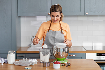 Image showing happy young woman cooking food on kitchen at home