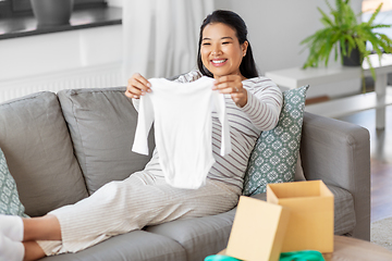 Image showing happy pregnant woman with baby's bodysuit at home