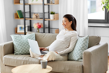 Image showing happy pregnant asian woman with laptop at home