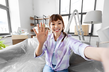 Image showing smiling asian woman taking selfie at new home