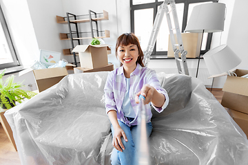 Image showing smiling asian woman taking selfie at new home