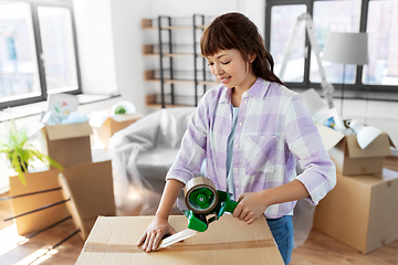 Image showing woman with adhesive tape packing box at new home