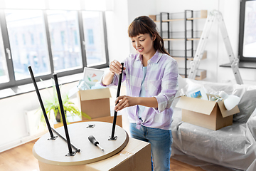 Image showing happy woman assembling coffee table at new home