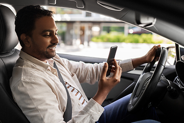 Image showing smiling indian man in car using smartphone