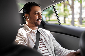 Image showing indian male passenger with earphones in taxi car