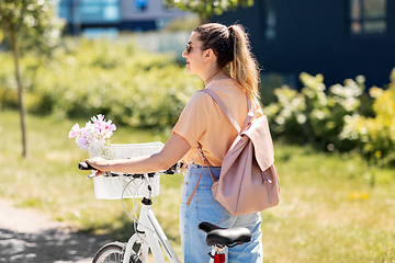 Image showing woman with flowers in bicycle basket in city