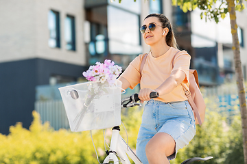 Image showing happy woman with earphones riding bicycle in city