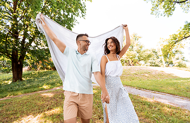 Image showing happy couple with picnic blanket at summer park