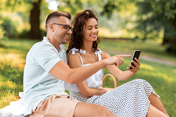 Image showing happy couple with smartphone at picnic in park