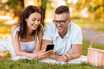 Image showing happy couple with smartphone at picnic in park