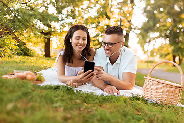 Image showing couple with earphones and smartphone at picnic