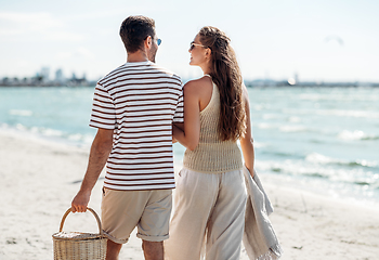 Image showing happy couple with picnic basket walking on beach