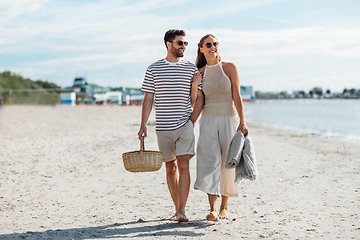 Image showing happy couple with picnic basket walking on beach