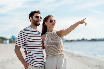 Image showing happy couple pointing finger on summer beach