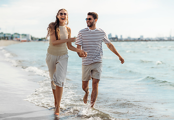 Image showing happy couple running along summer beach