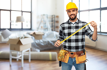 Image showing happy male builder in helmet with ruler at home