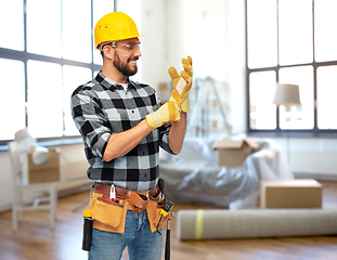 Image showing happy male builder in helmet and gloves at home