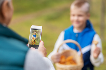 Image showing grandmother photographing grandson with mushrooms