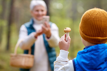 Image showing grandmother photographing grandson with mushroom