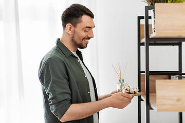 Image showing man placing aroma reed diffuser to shelf home