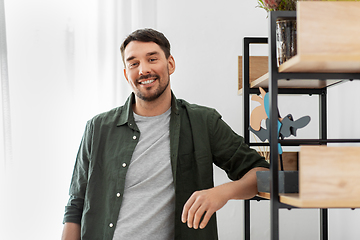 Image showing happy smiling man standing at shelf at home