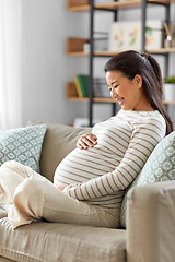 Image showing happy pregnant asian woman sitting on sofa at home