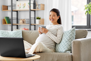 Image showing happy pregnant asian woman with laptop at home