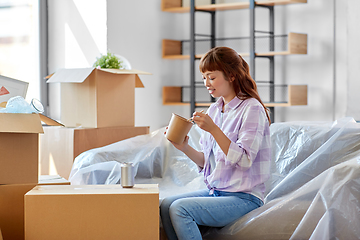 Image showing happy woman moving to new home and eating wok