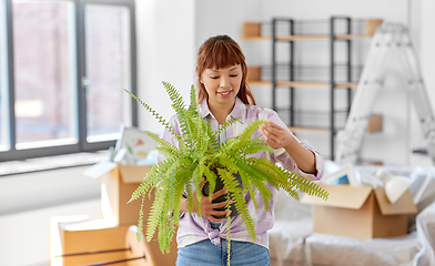 Image showing happy woman with fern flower moving to new home