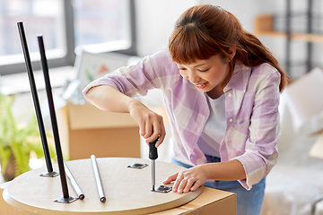 Image showing happy woman assembling coffee table at new home