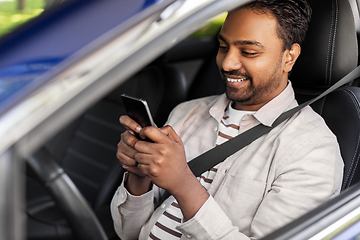 Image showing smiling indian man in car using smartphone