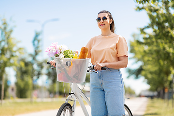 Image showing woman with food and flowers in bicycle basket