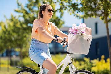 Image showing woman with flowers in bicycle basket in city