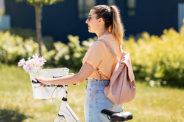Image showing woman with flowers in bicycle basket in city