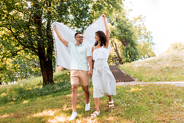 Image showing happy couple with picnic blanket at summer park