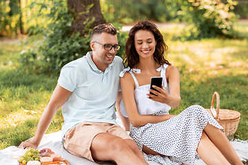 Image showing happy couple with smartphone at picnic in park