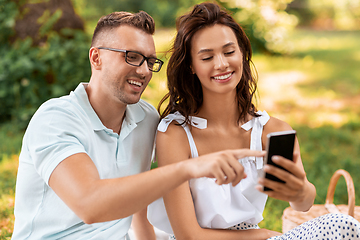 Image showing happy couple with smartphone at picnic in park