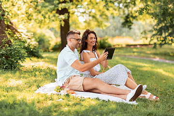 Image showing happy couple with tablet pc at picnic in park