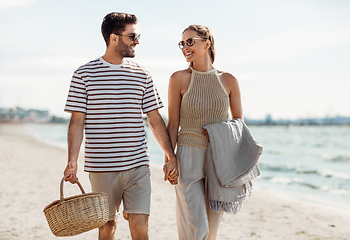 Image showing happy couple with picnic basket walking on beach