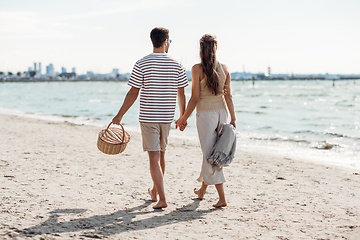 Image showing happy couple with picnic basket walking on beach