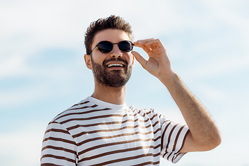 Image showing smiling young man in sunglasses over sky